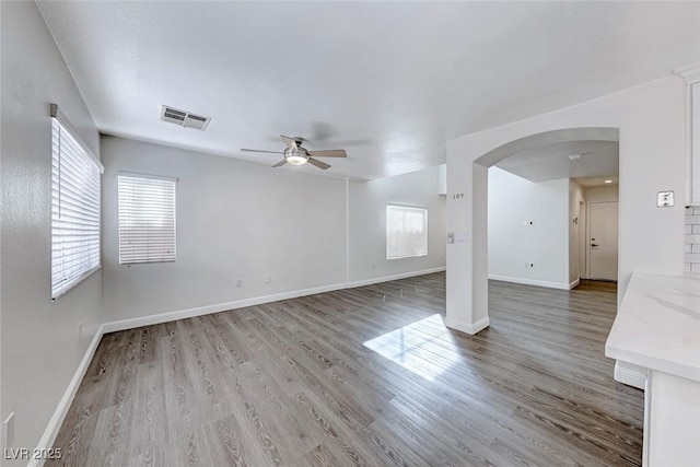 11028 Meadow Leaf Ave, Las Vegas, NV 89144 - unfurnished living room with arched walkways, ceiling fan, wood finished floors, and baseboards