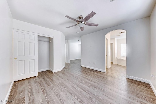 11028 Meadow Leaf Ave, Las Vegas, NV 89144 - unfurnished bedroom featuring arched walkways, light wood-type flooring, baseboards, a closet, and a ceiling fan