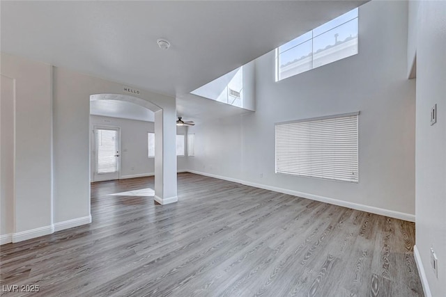 11028 Meadow Leaf Ave, Las Vegas, NV 89144 - unfurnished living room featuring arched walkways, wood finished floors, and baseboards