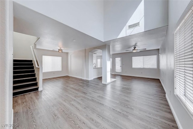11028 Meadow Leaf Ave, Las Vegas, NV 89144 - unfurnished living room with ceiling fan, wood finished floors, arched walkways, stairs, and baseboards