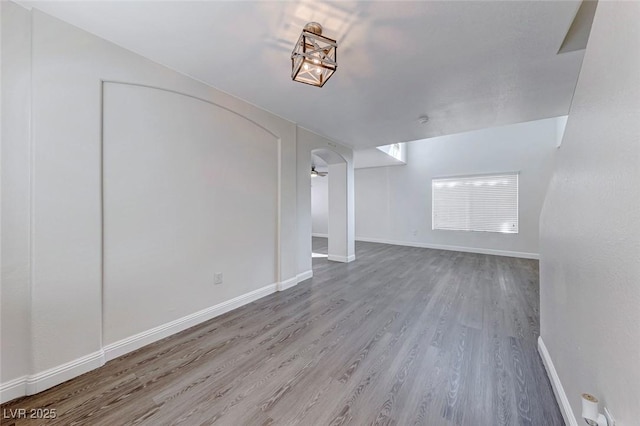 11028 Meadow Leaf Ave, Las Vegas, NV 89144 - unfurnished living room featuring wood finished floors, arched walkways, and baseboards