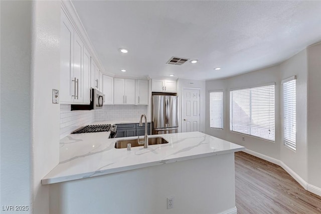 11028 Meadow Leaf Ave, Las Vegas, NV 89144 - kitchen featuring stainless steel appliances, a sink, light stone countertops, a peninsula, and white cabinets