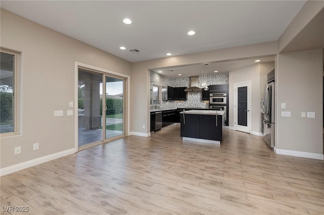 2900 Valvent Ct, Henderson, NV 89044 - kitchen featuring appliances with stainless steel finishes, wall chimney range hood, dark cabinetry, decorative backsplash, and open floor plan
