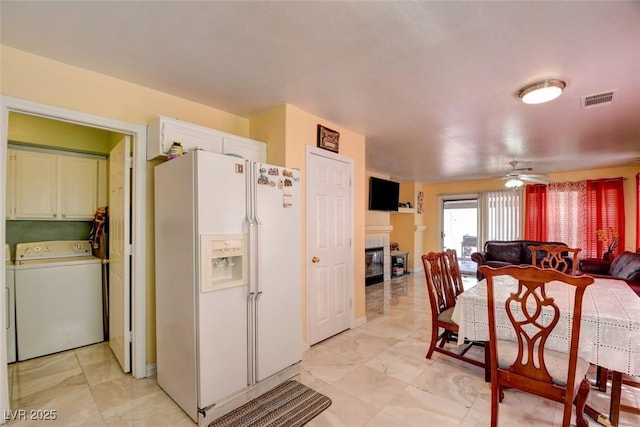 8370 Lost Lake Ct, Las Vegas, NV 89147 - kitchen with white refrigerator with ice dispenser, washer / clothes dryer, a fireplace, ceiling fan, and light marble finish flooring