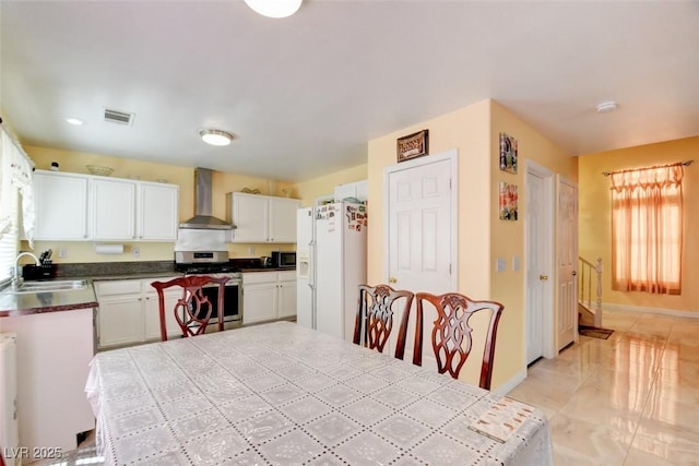 8370 Lost Lake Ct, Las Vegas, NV 89147 - kitchen featuring stainless steel range with gas stovetop, wall chimney exhaust hood, a sink, white refrigerator with ice dispenser, and white cabinets