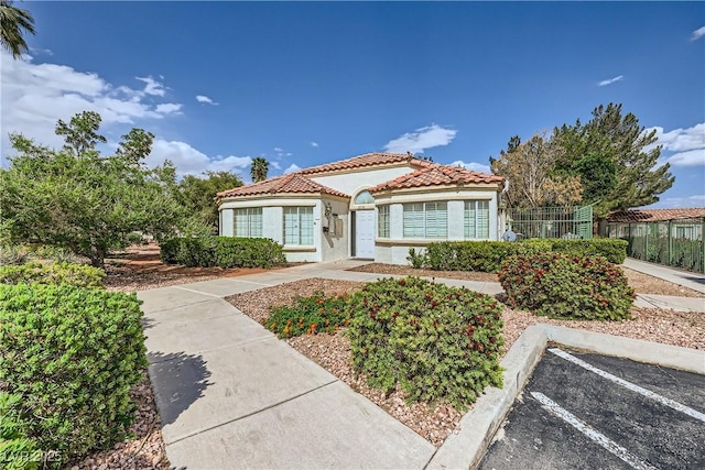 5401 Bugle Way Unit 103, Las Vegas, NV 89108 - mediterranean / spanish-style home featuring a tile roof, stucco siding, uncovered parking, and fence