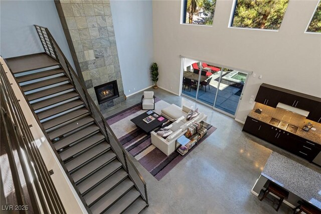 2672 Mystere Ct, Las Vegas, NV 89117 - living area with a towering ceiling, a tile fireplace, stairway, and finished concrete floors