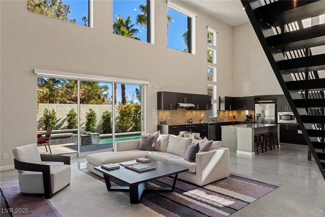 2672 Mystere Ct, Las Vegas, NV 89117 - living room featuring healthy amount of natural light, a towering ceiling, finished concrete flooring, and stairway