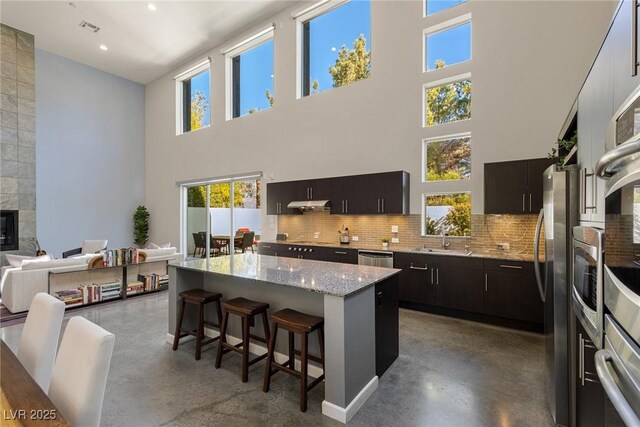 2672 Mystere Ct, Las Vegas, NV 89117 - kitchen with finished concrete flooring, a breakfast bar area, tasteful backsplash, a towering ceiling, and a kitchen island