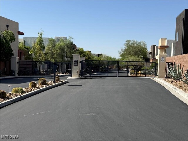 2672 Mystere Ct, Las Vegas, NV 89117 - view of asphalt road featuring a gate, a gated entry, and curbs