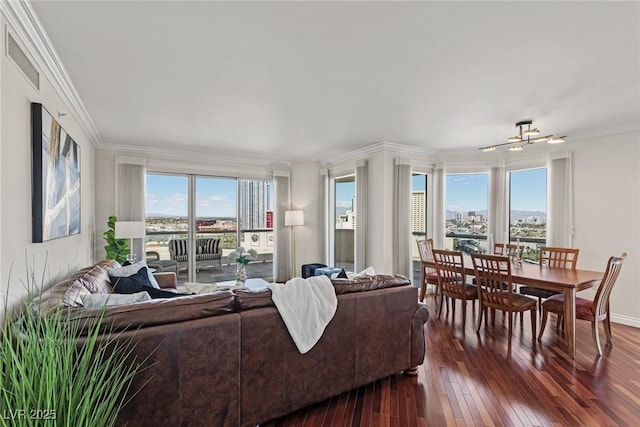 living room featuring dark wood-type flooring, healthy amount of natural light, crown molding, baseboards, and a chandelier