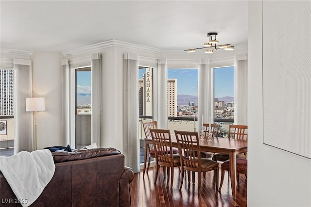 dining area featuring hardwood / wood-style floors, a chandelier, crown molding, and a view of city