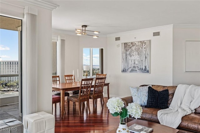 living area featuring ornamental molding, wood finished floors, and a chandelier