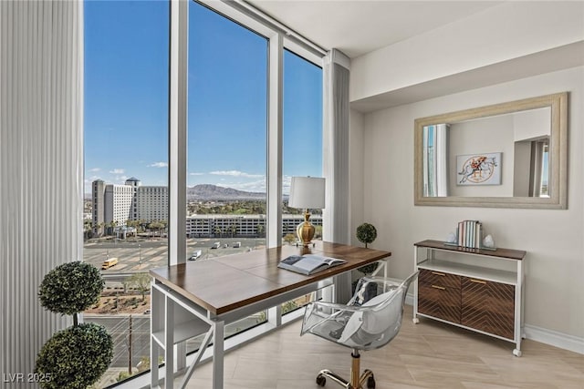 office space with a mountain view, expansive windows, and baseboards