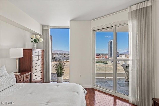 bedroom featuring hardwood / wood-style floors, access to outside, a wall of windows, and baseboards