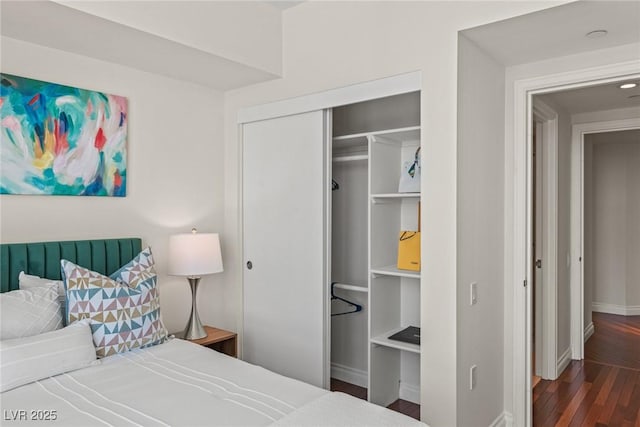 bedroom with a closet, baseboards, and wood finished floors
