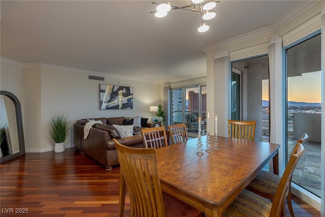 dining space featuring wood finished floors, a chandelier, ornamental molding, and baseboards