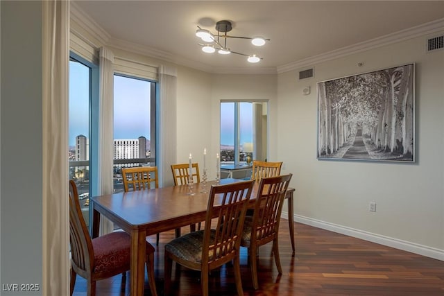 dining area featuring dark wood finished floors, a chandelier, ornamental molding, and baseboards