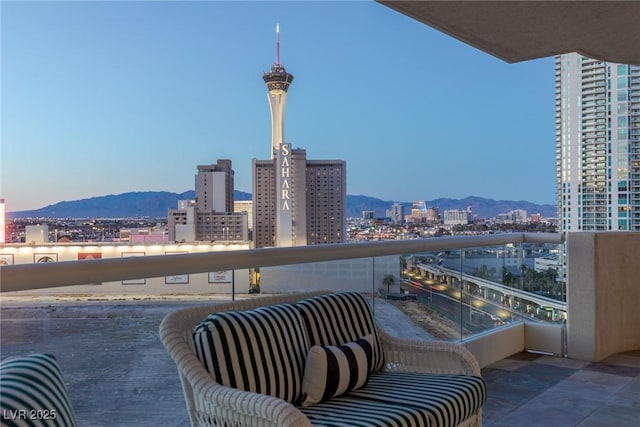 balcony at dusk featuring a city view and a mountain view