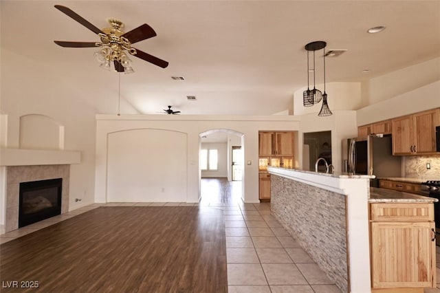 6016 Bungalow Bay St, Las Vegas, NV 89130 - kitchen featuring ceiling fan, open floor plan, stainless steel fridge, an island with sink, and arched walkways