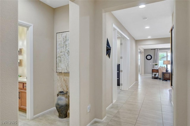 hall featuring light tile patterned flooring, baseboards, and recessed lighting