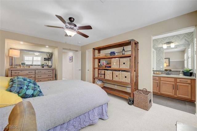 bedroom featuring ensuite bathroom, a ceiling fan, and light colored carpet