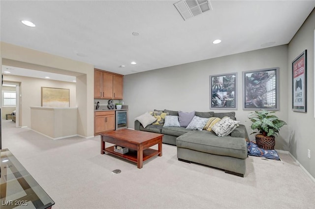 living area featuring beverage cooler, recessed lighting, light carpet, baseboards, and bar