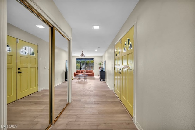 corridor with light wood-style floors and baseboards