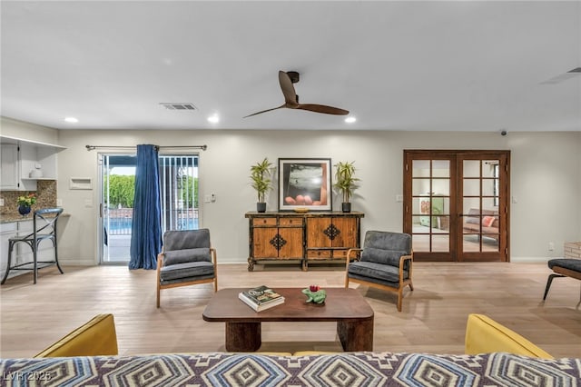 living area featuring french doors, a ceiling fan, recessed lighting, light wood-type flooring, and baseboards