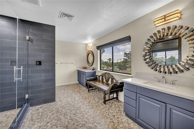 bathroom with tiled shower, vanity, and baseboards
