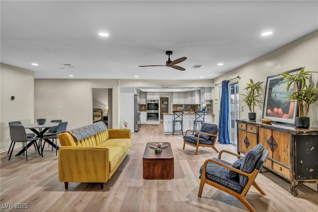 living area featuring light wood finished floors, a ceiling fan, and recessed lighting