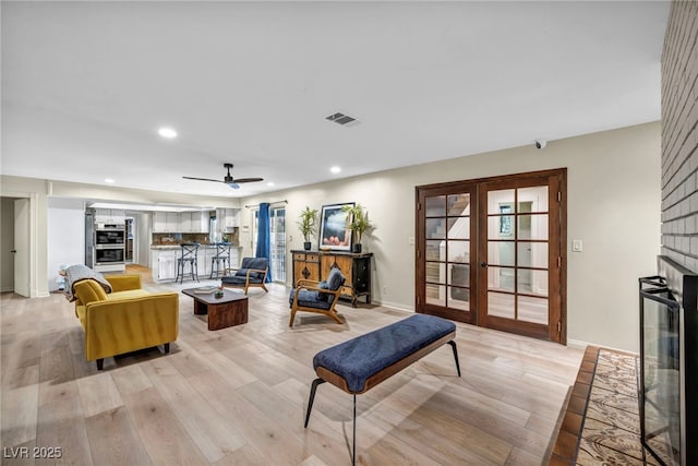 living area featuring french doors, light wood-style floors, recessed lighting, a fireplace, and ceiling fan