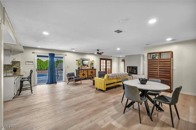 dining space with a fireplace, light wood-style floors, recessed lighting, healthy amount of natural light, and a ceiling fan