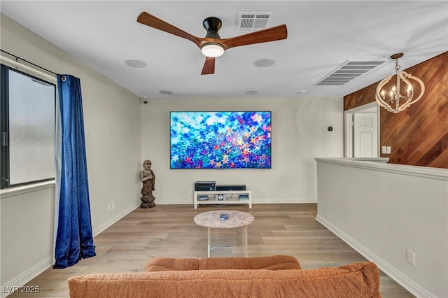 home theater with a chandelier, a ceiling fan, baseboards, and wood finished floors