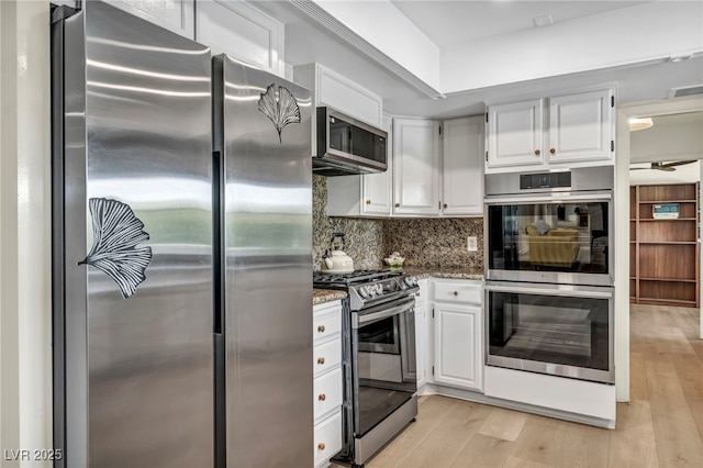 kitchen featuring appliances with stainless steel finishes, stone counters, light wood-style floors, tasteful backsplash, and white cabinets