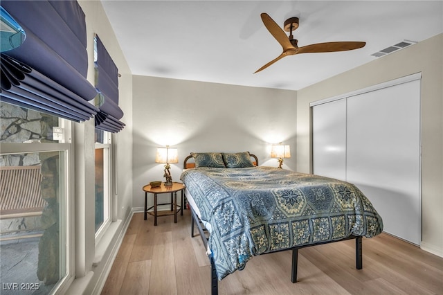 bedroom with wood finished floors, a closet, a ceiling fan, and baseboards