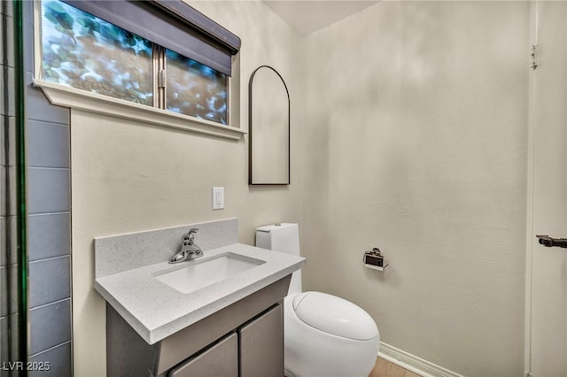 bathroom featuring toilet, vanity, and baseboards