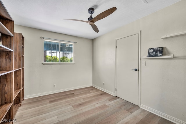 unfurnished room with ceiling fan, light wood finished floors, and baseboards