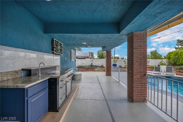 view of patio with a sink, an outdoor kitchen, and fence