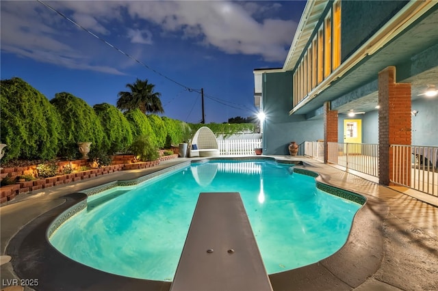 view of swimming pool with fence and a diving board
