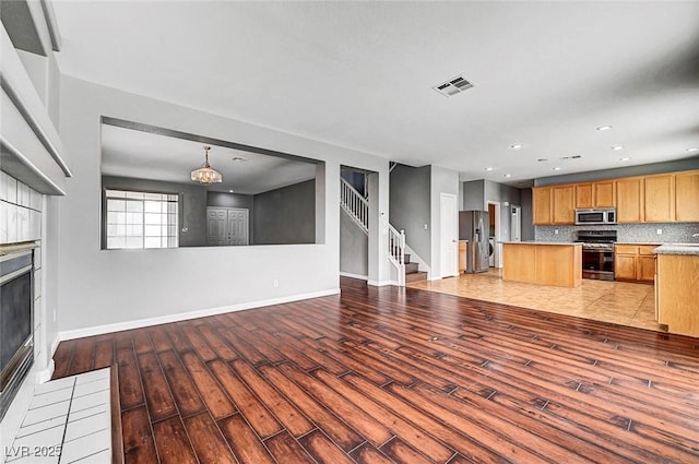 10135 Diving Duck Ave, Las Vegas, NV 89117 - kitchen with stainless steel appliances, light wood-type flooring, a kitchen island, a tile fireplace, and light countertops