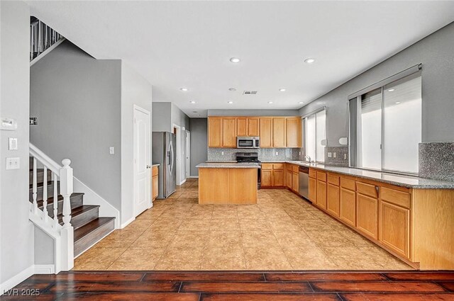 10135 Diving Duck Ave, Las Vegas, NV 89117 - kitchen with appliances with stainless steel finishes, a kitchen island, backsplash, recessed lighting, and light wood finished floors