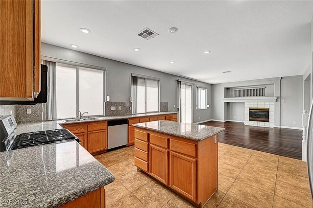 10135 Diving Duck Ave, Las Vegas, NV 89117 - kitchen with stainless steel appliances, a center island, decorative backsplash, a fireplace, and dark stone countertops