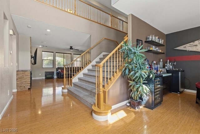 8723 Melissa Meadows St, Las Vegas, NV 89131 - stairway with wood finished floors, baseboards, bar, ceiling fan, and a towering ceiling