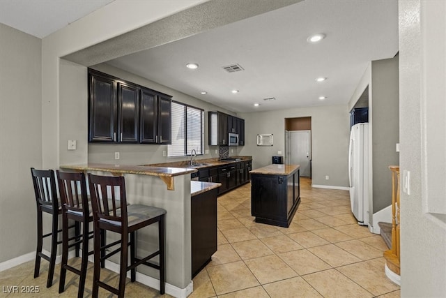 8723 Melissa Meadows St, Las Vegas, NV 89131 - kitchen featuring dark cabinets, appliances with stainless steel finishes, a sink, a kitchen island, and recessed lighting