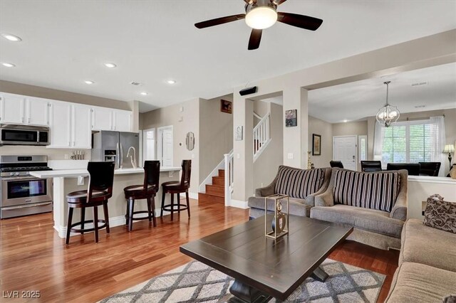 10046 Floragold Ct, Las Vegas, NV 89147 - living area featuring stairs, recessed lighting, light wood finished floors, a ceiling fan, and a chandelier