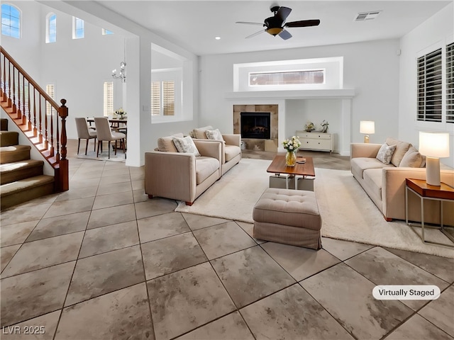 10056 Cranbrook Falls Ct, Las Vegas, NV 89148 - tiled living room with stairway, a ceiling fan, a fireplace, and a chandelier