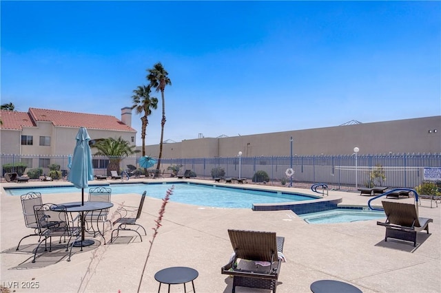 community pool with fence and a patio area