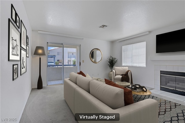 living room with a tile fireplace and light carpet