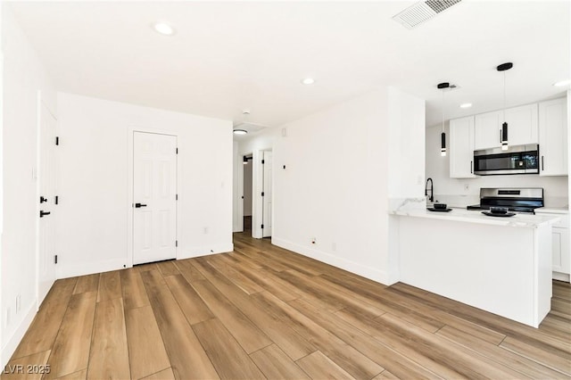 kitchen featuring appliances with stainless steel finishes, light wood finished floors, recessed lighting, white cabinetry, and baseboards